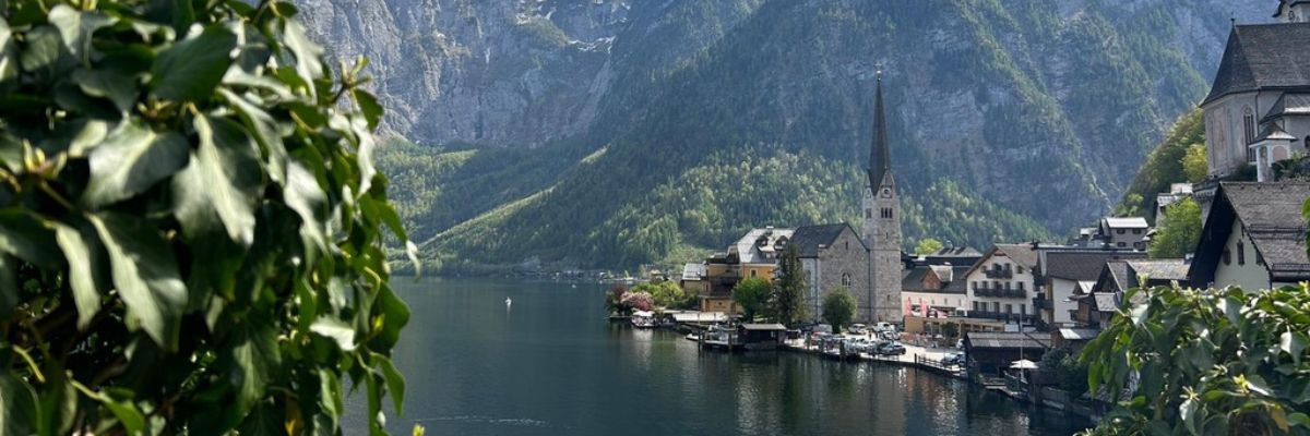Scenic view of Hallstatt, Austria with alpine village, church steeple, lake, and surrounding mountains