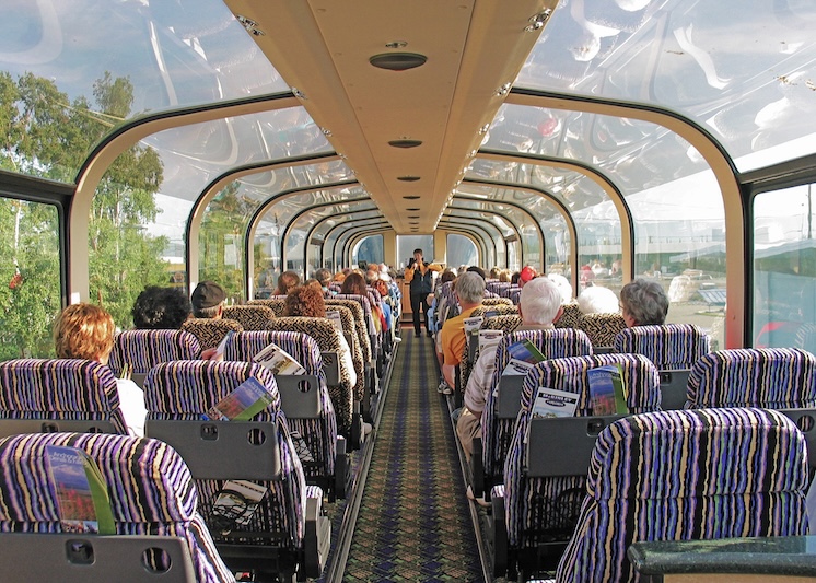 The inside of a train with lots of windows for seeing the scenery