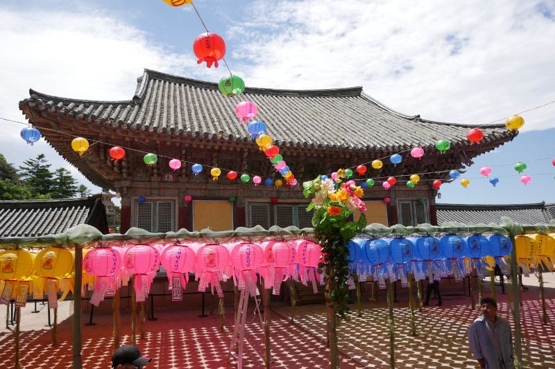 Vibrant lanterns hanging in front of a traditional Korean temple under a bright blue sky during a cultural celebration.