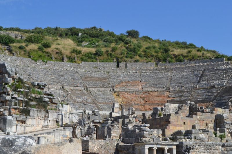 Historic Roman amphitheater in Ephesus Turkey with stone seating and green hillside