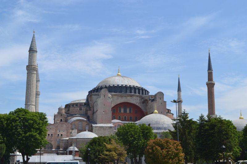 Exterior view of Hagia Sophia in Istanbul Turkey with domes and minarets on sunny day