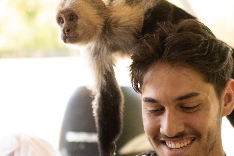 Smiling man with a monkey perched on his shoulder in Costa Rica.