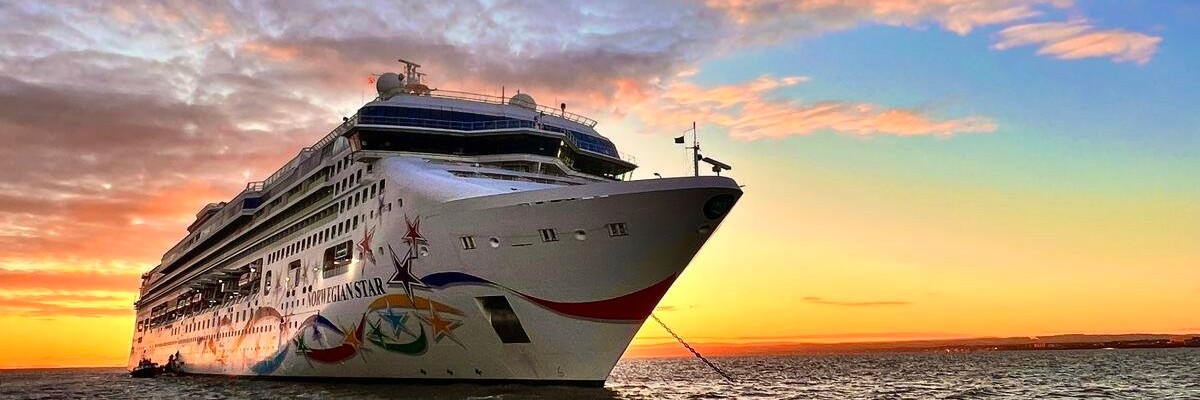 cruise ship on water with sun setting behind