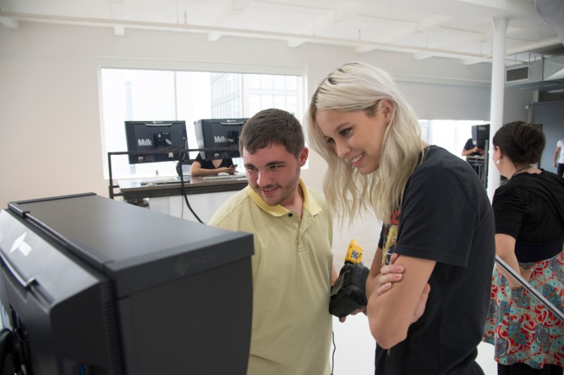 Photographer and model reviewing images on a monitor in a bright professional studio.