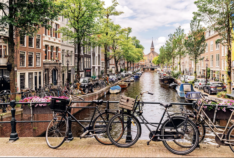Bikes parked along a railing on a bridge passing over a canal