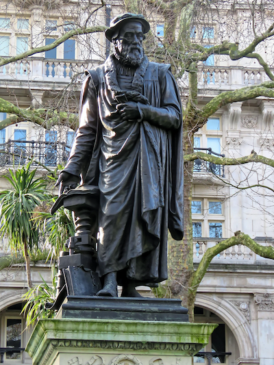 A statue of a man in front of a tree